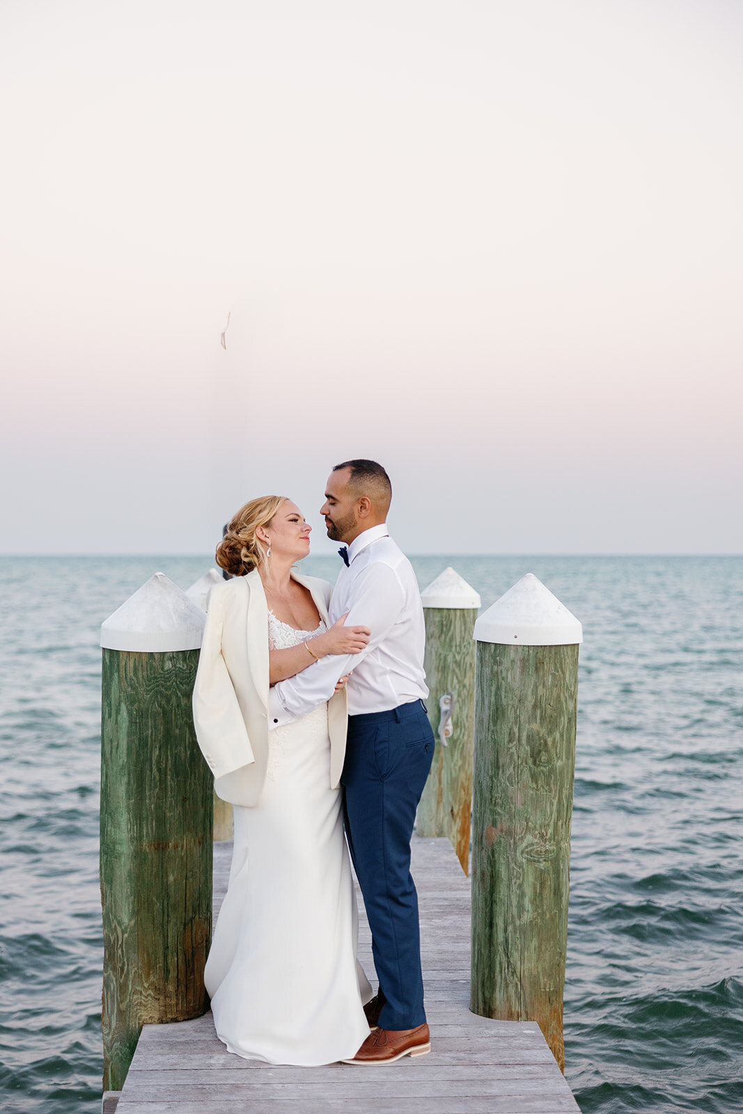 Bride and groom standing on a wooden pier with ocean views at their Islamorada destination wedding.