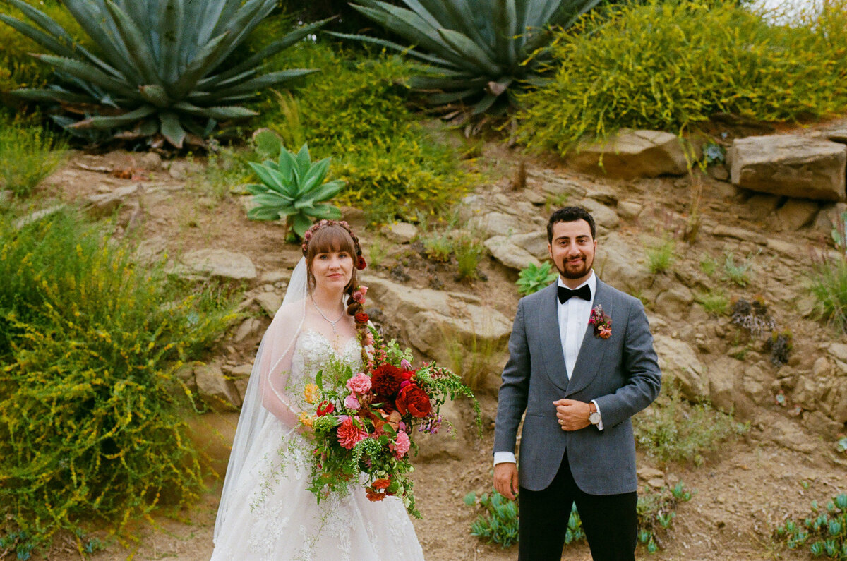 A bride and groom standing in a small garden area.