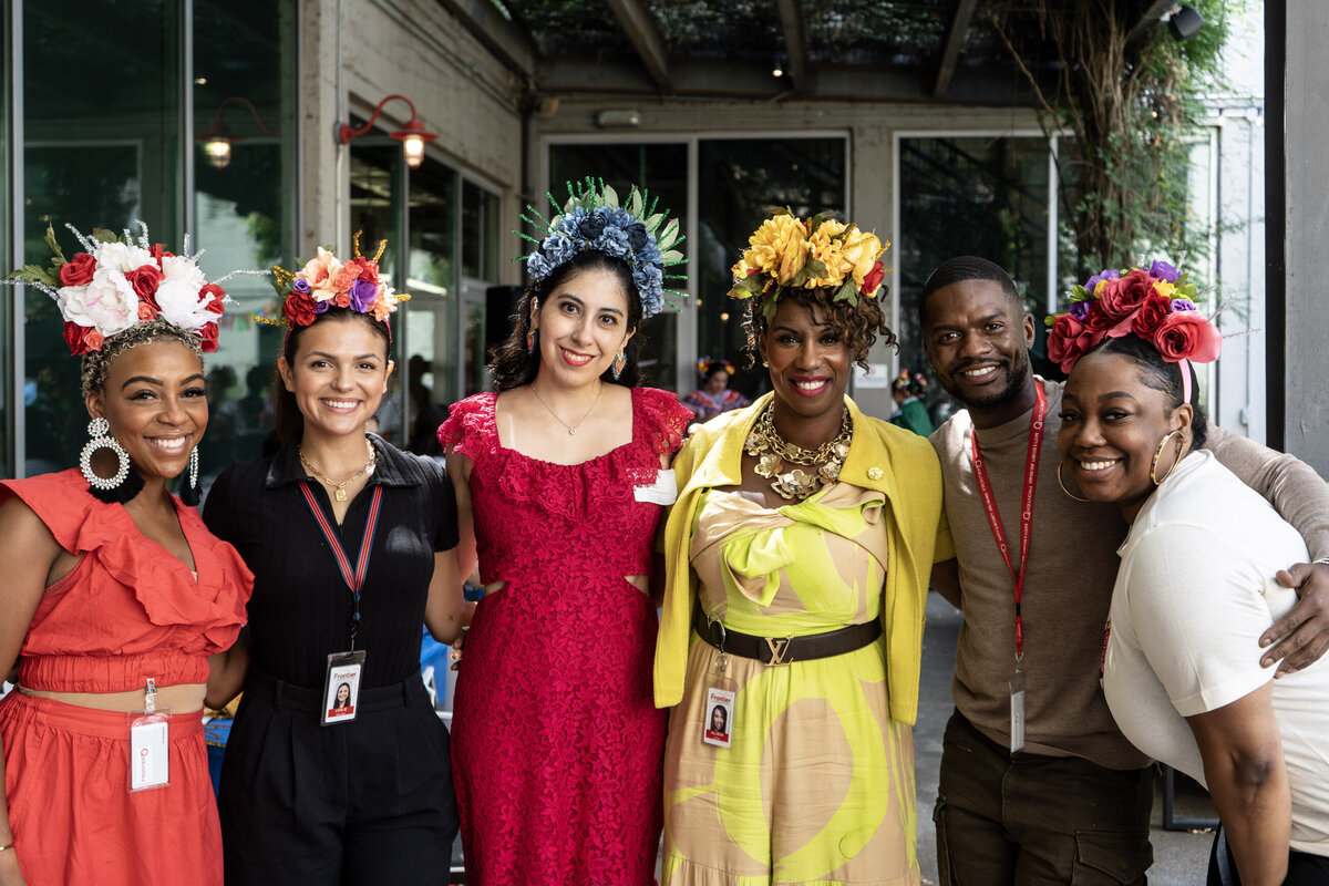 Women proudly display their artistic creations at Soleil Vida Studio's art workshop. Dressed in an array of colorful dresses, each adorned with a personally crafted flower crown, they beam with joy