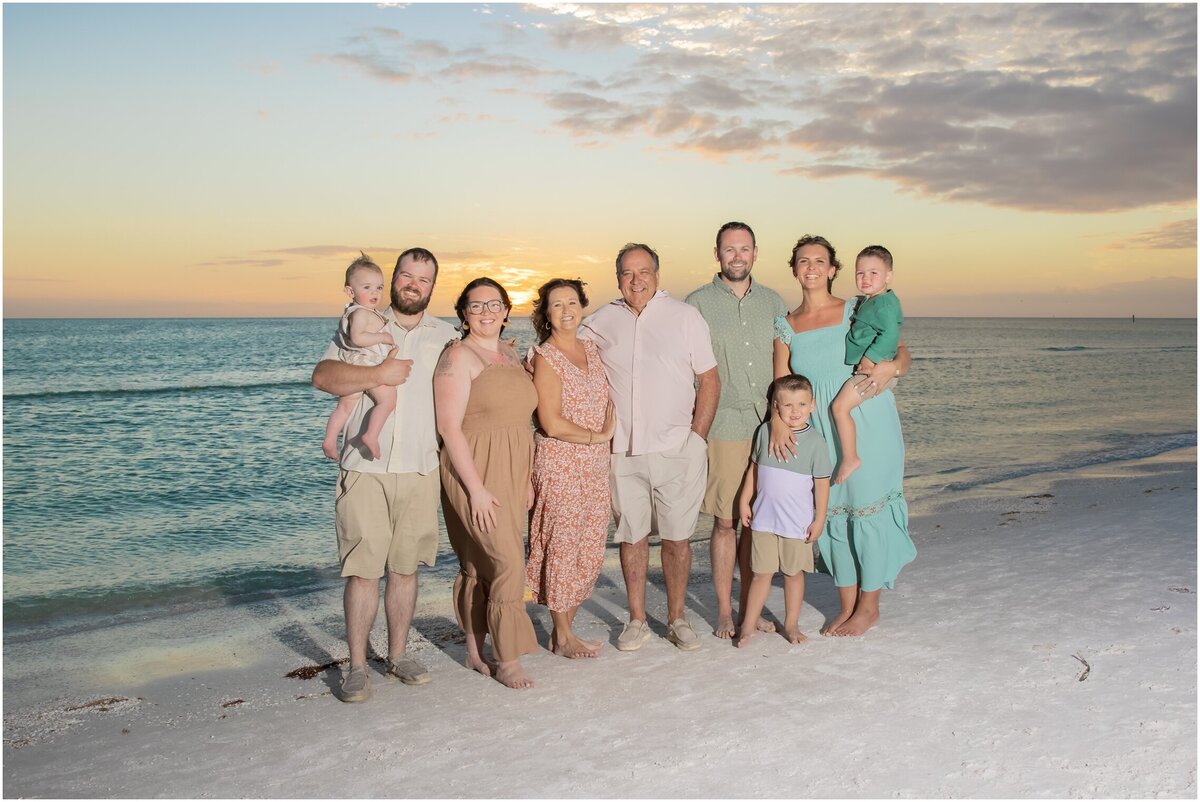 Portrait of a family of nine on the beach wearing blush and turquoise