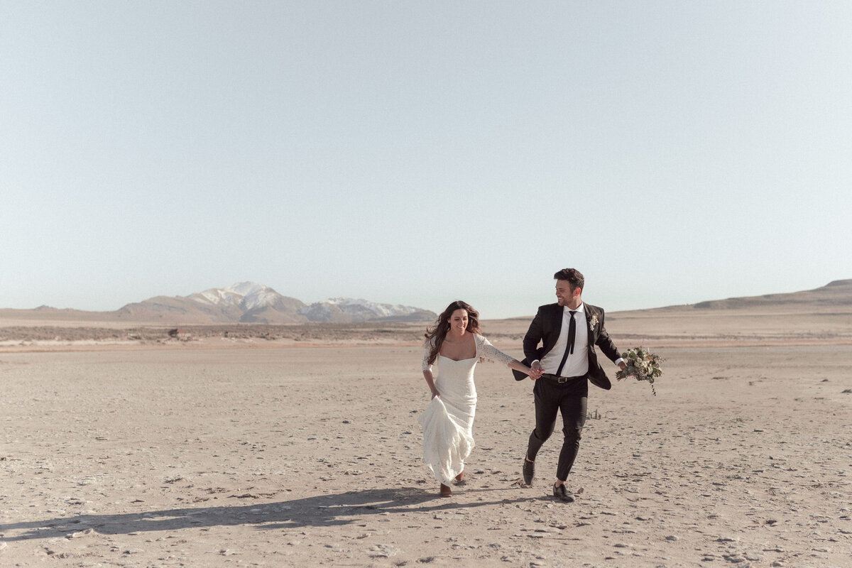 bride and groom holding hands running