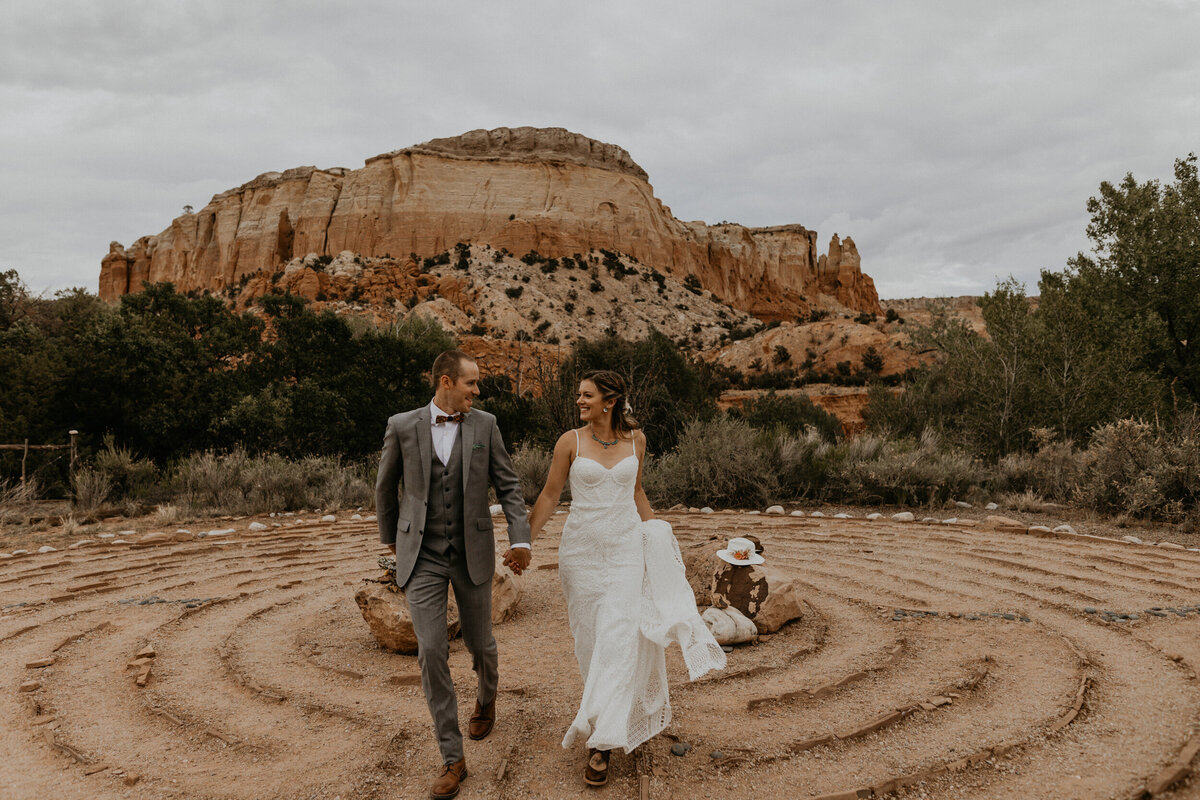 bride and groom running in front of red rocks together
