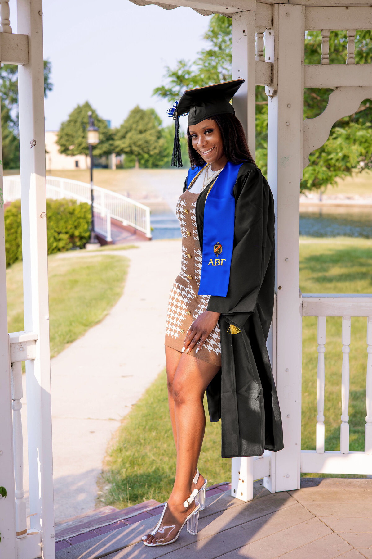 College graduate wearing black graduation cap and gown in a gazebo