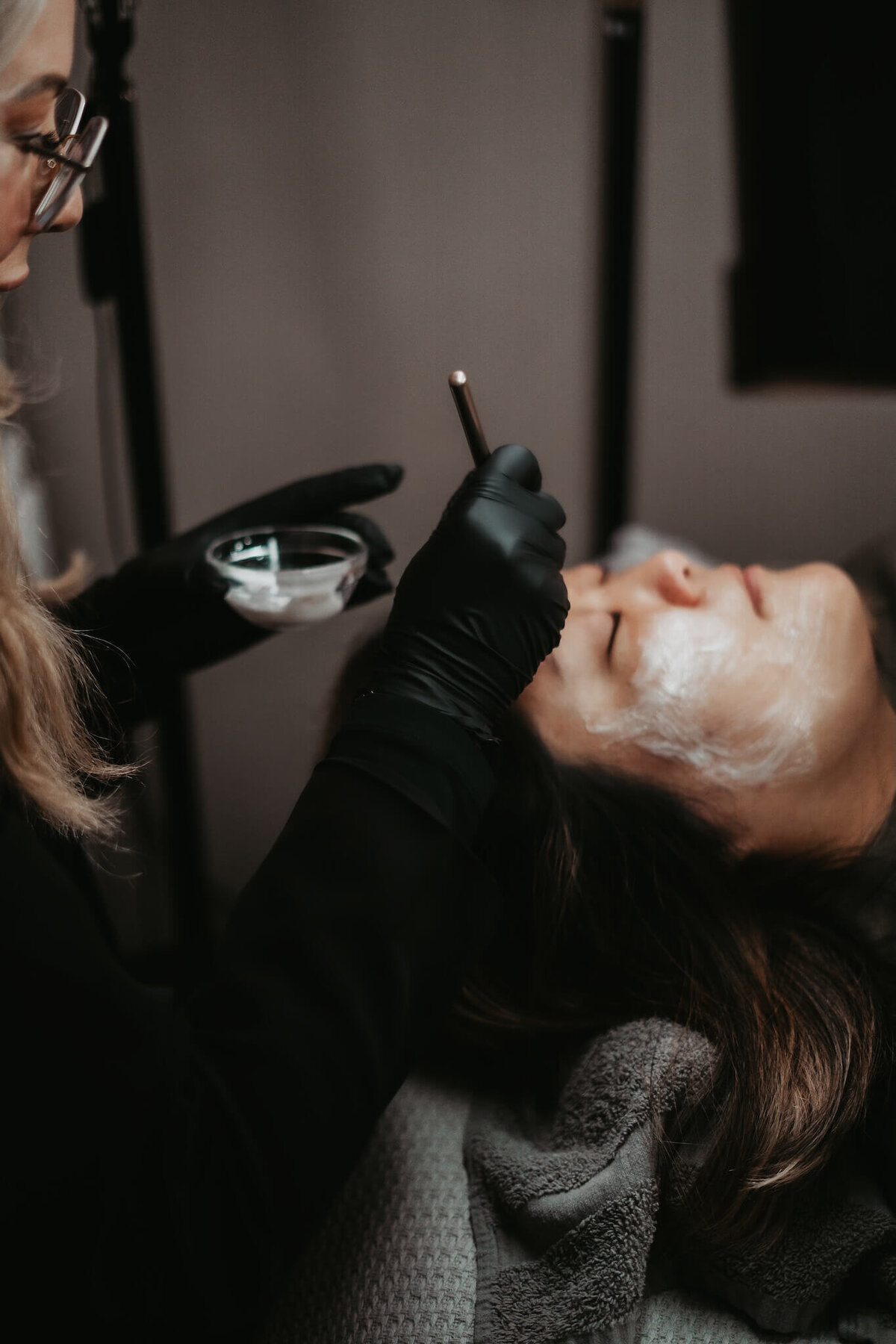 Esthetician in Appleton Wi applying a moisturizing face cream to a client as she closes her eyes