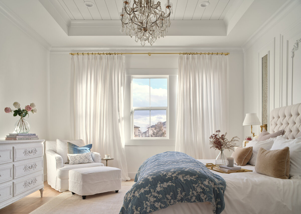 luxury bedroom with white dresser white sitting chiar and bed with blue blanket