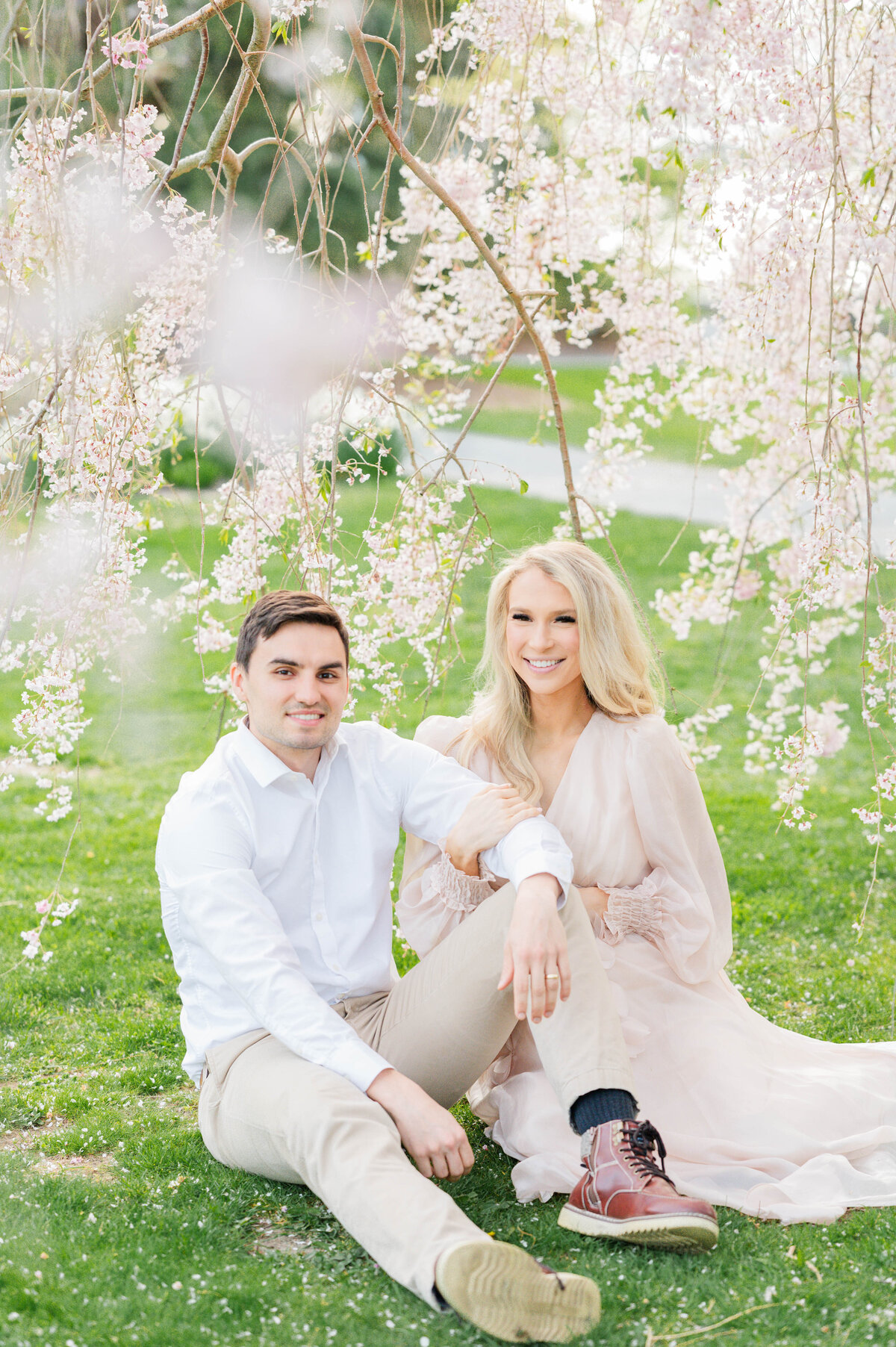 Husband and wife sitting with blooms around in Bristol, RI at Blithewold Mansion taken by best Maternity photographer in Rhode Island