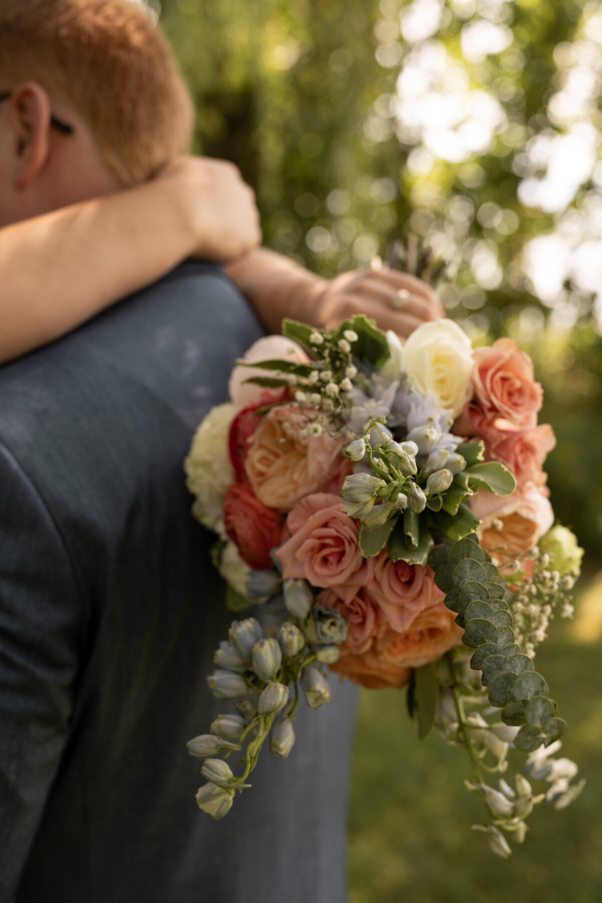 Bride's bouquet over groom's back taken by wedding photographers in Idaho.
