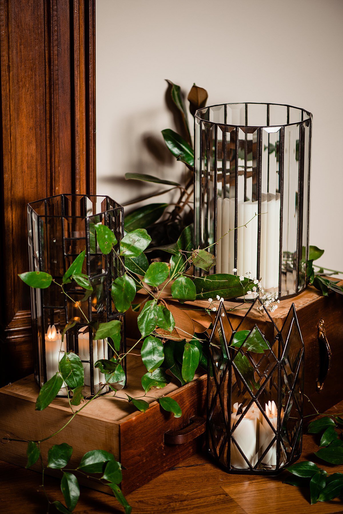 beveled glass candle holders with white pillar candles and greenery