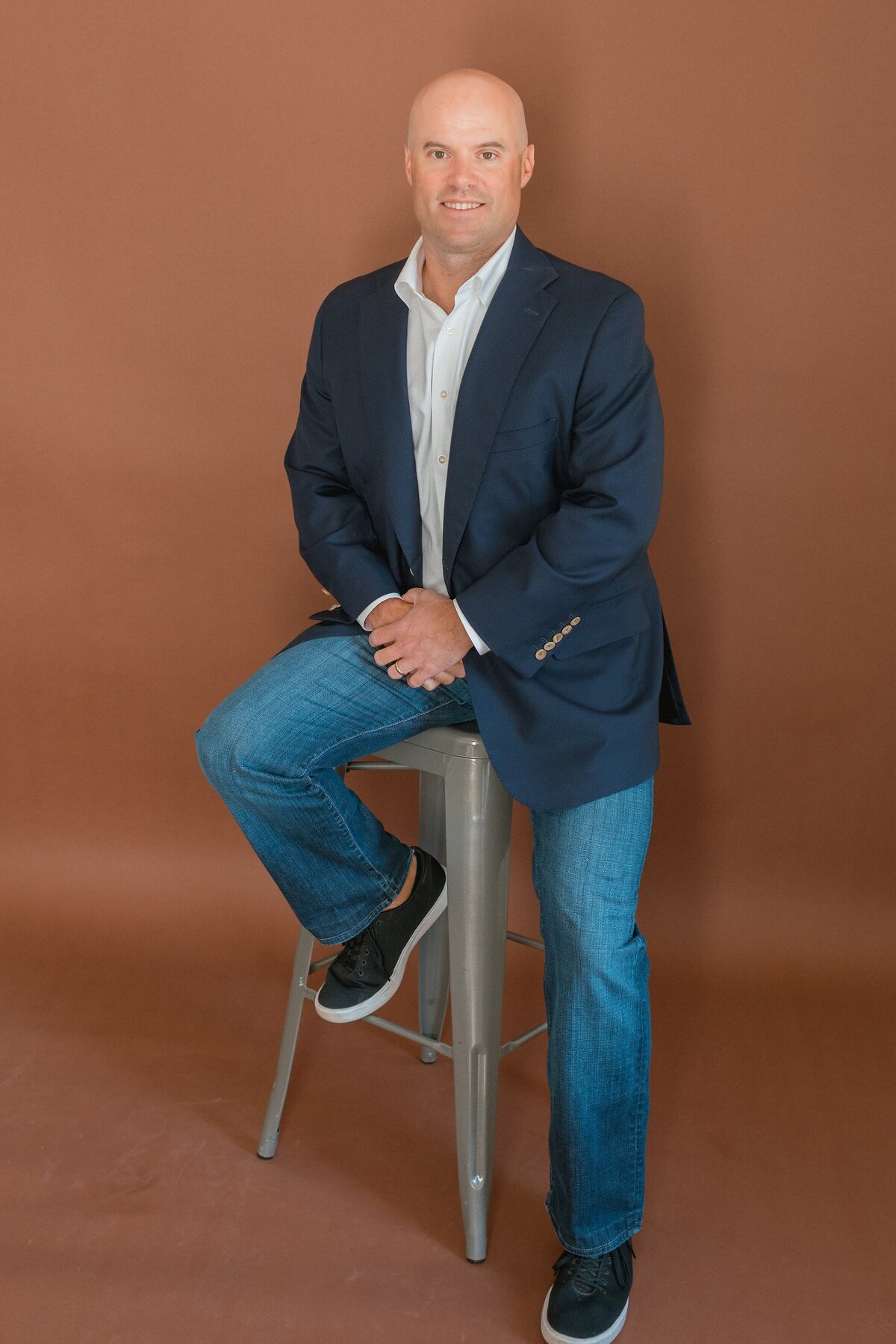 social media mangement owner sitting on a stool smiling at the camera