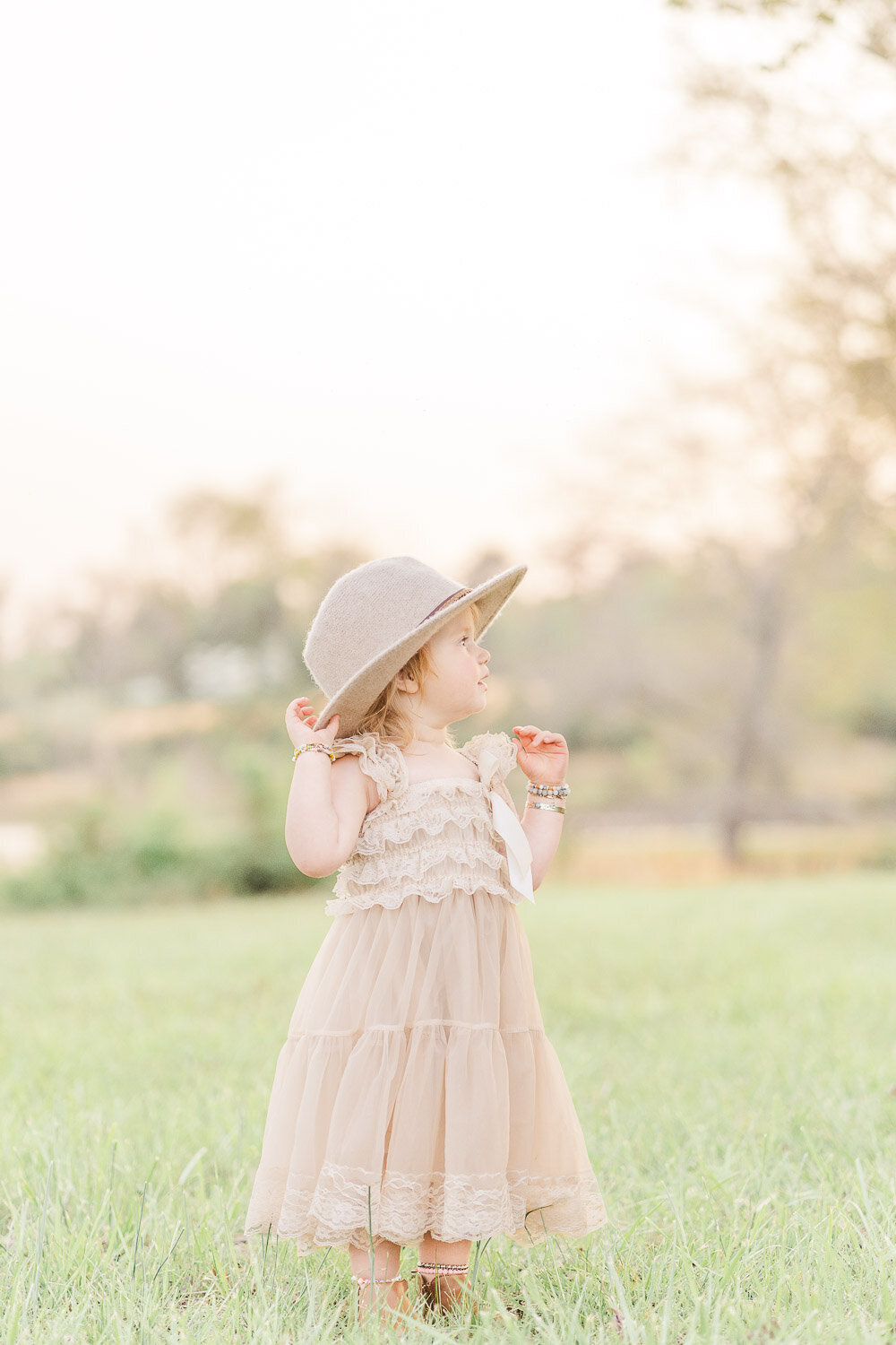 toddler holding on her hat during spring minis taken by Herndon, Virginia photographer