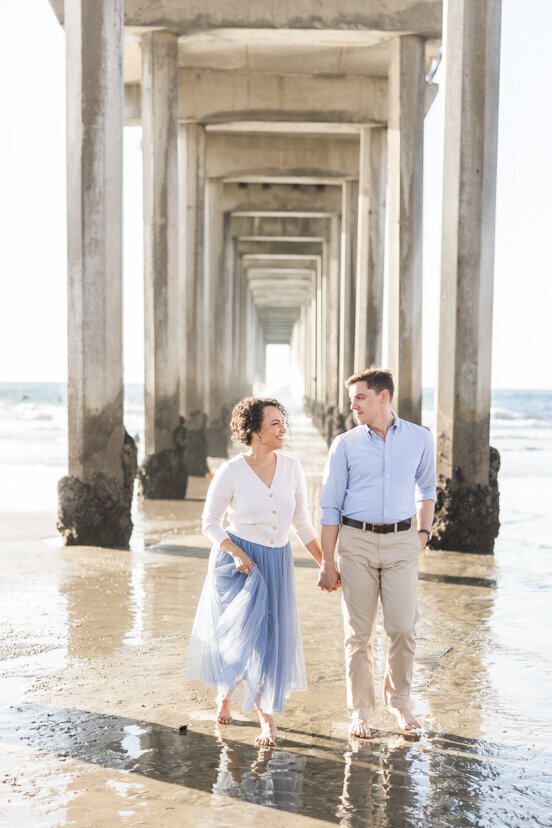 engaged-couple-walking-under-Scripps-Pier-San-Diego