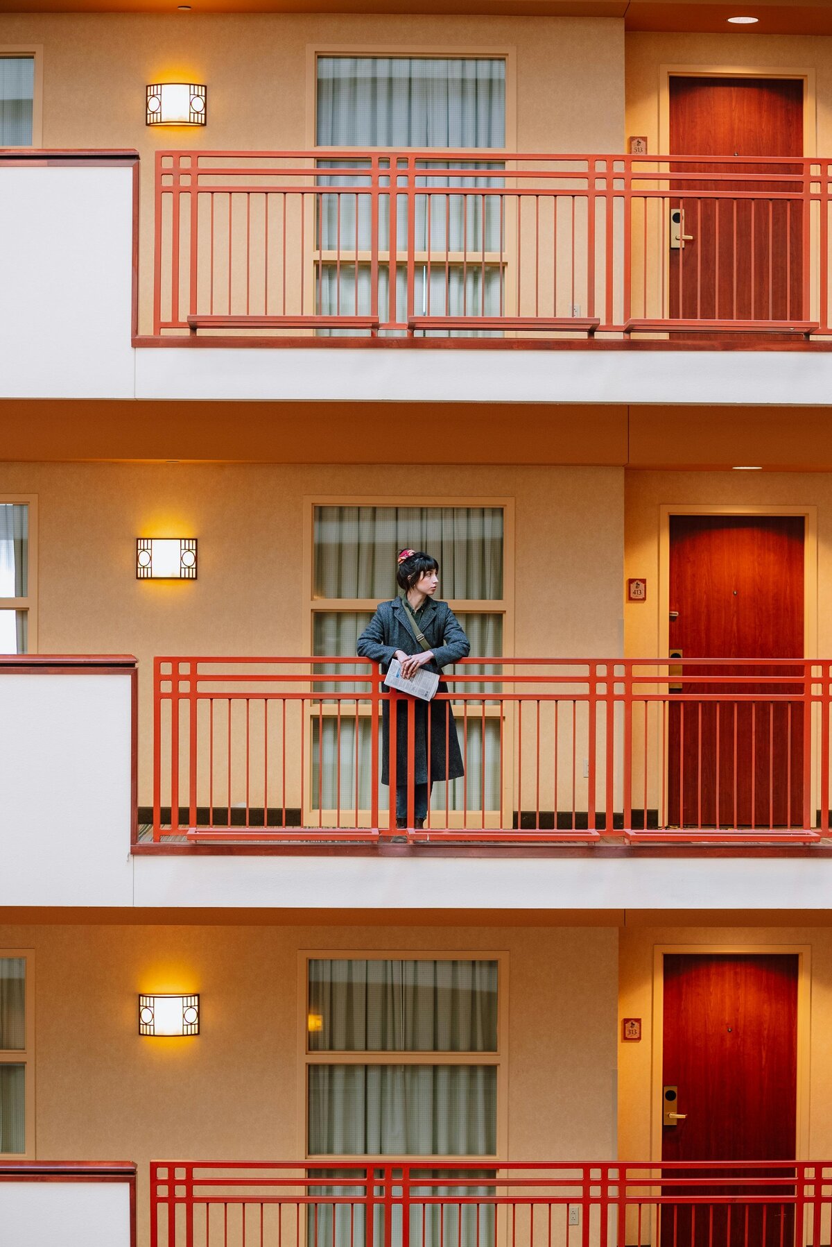 Repetitive view of hotel or apartment balconies, with a person standing on the middle level.