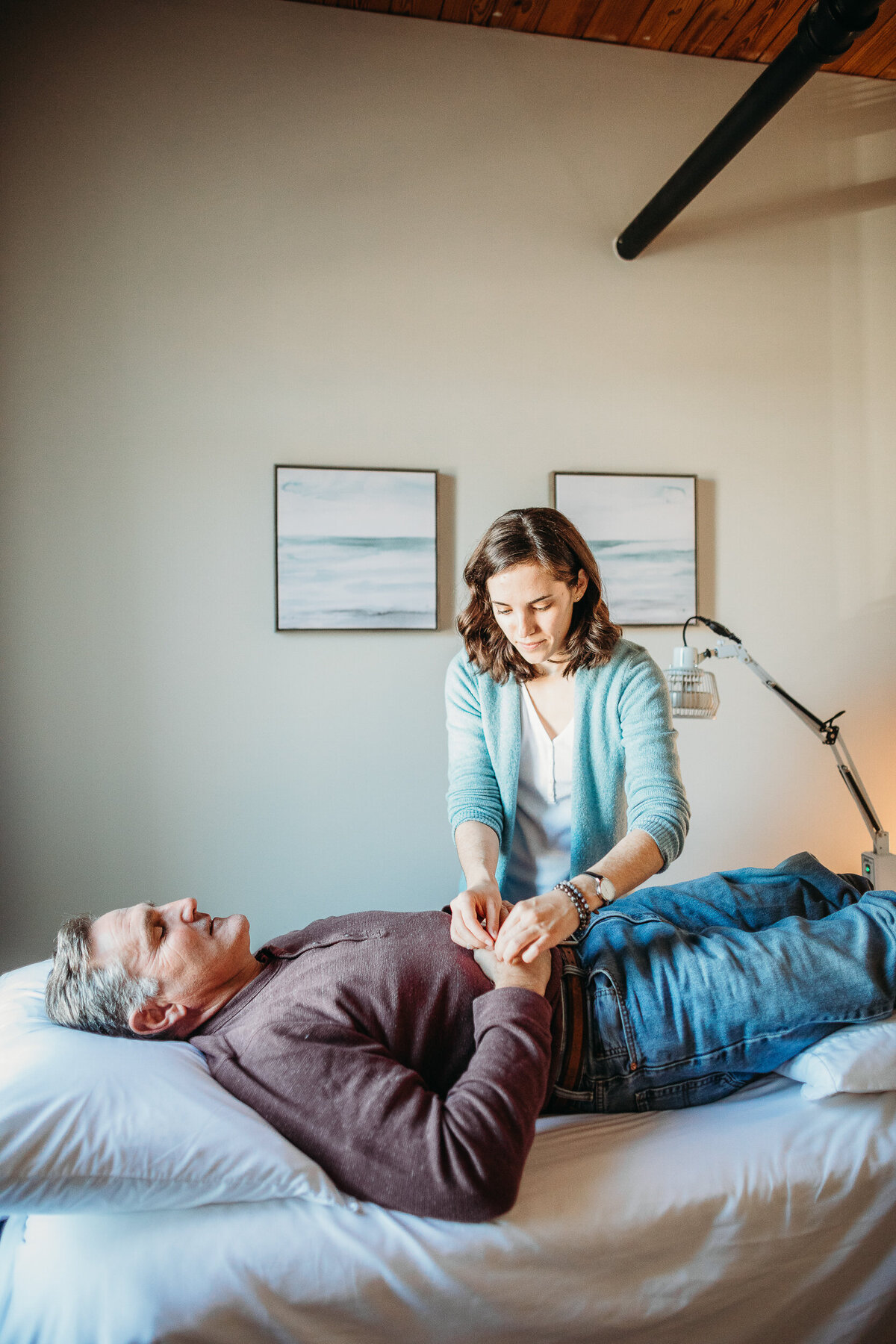 acupuncture puts needles into mans hand who is laying on table