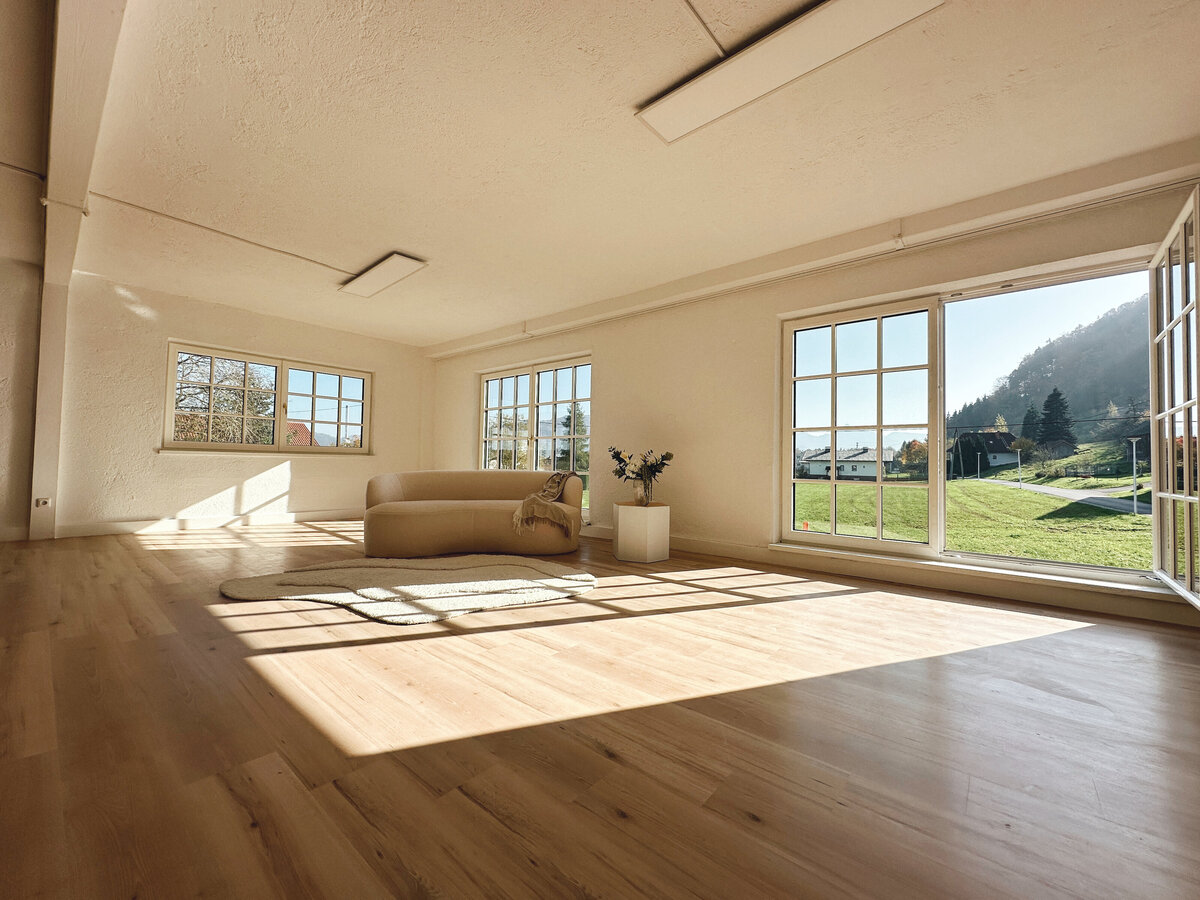 Bodentiefe Sprossenfenster im Atelier April, die reichlich Tageslicht hereinlassen und eine einladende Atmosphäre schaffen.