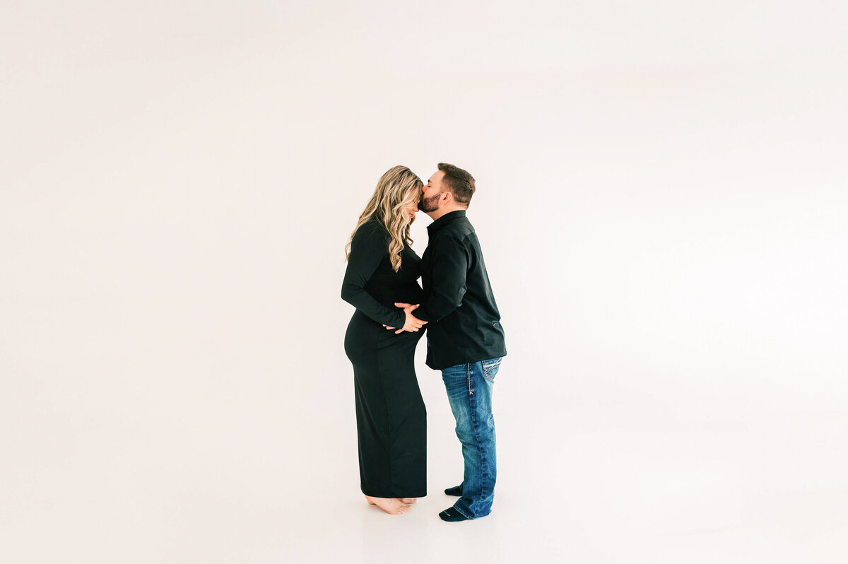 husband kissing pregnant wife forehead in Springfield Mo maternity photography studio