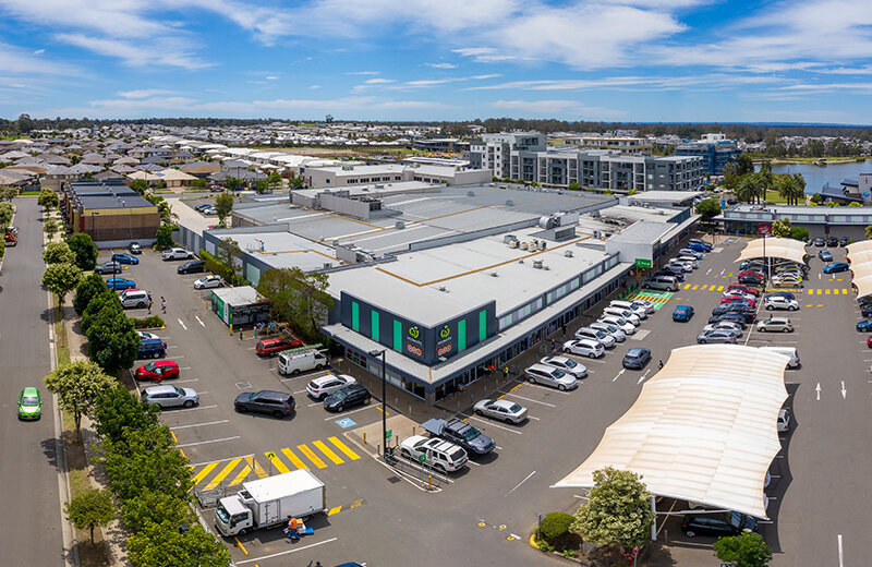 Aerial view of Jordan Springs Shopping Centre highlighting the building layout, parking area, and surrounding commercial development.