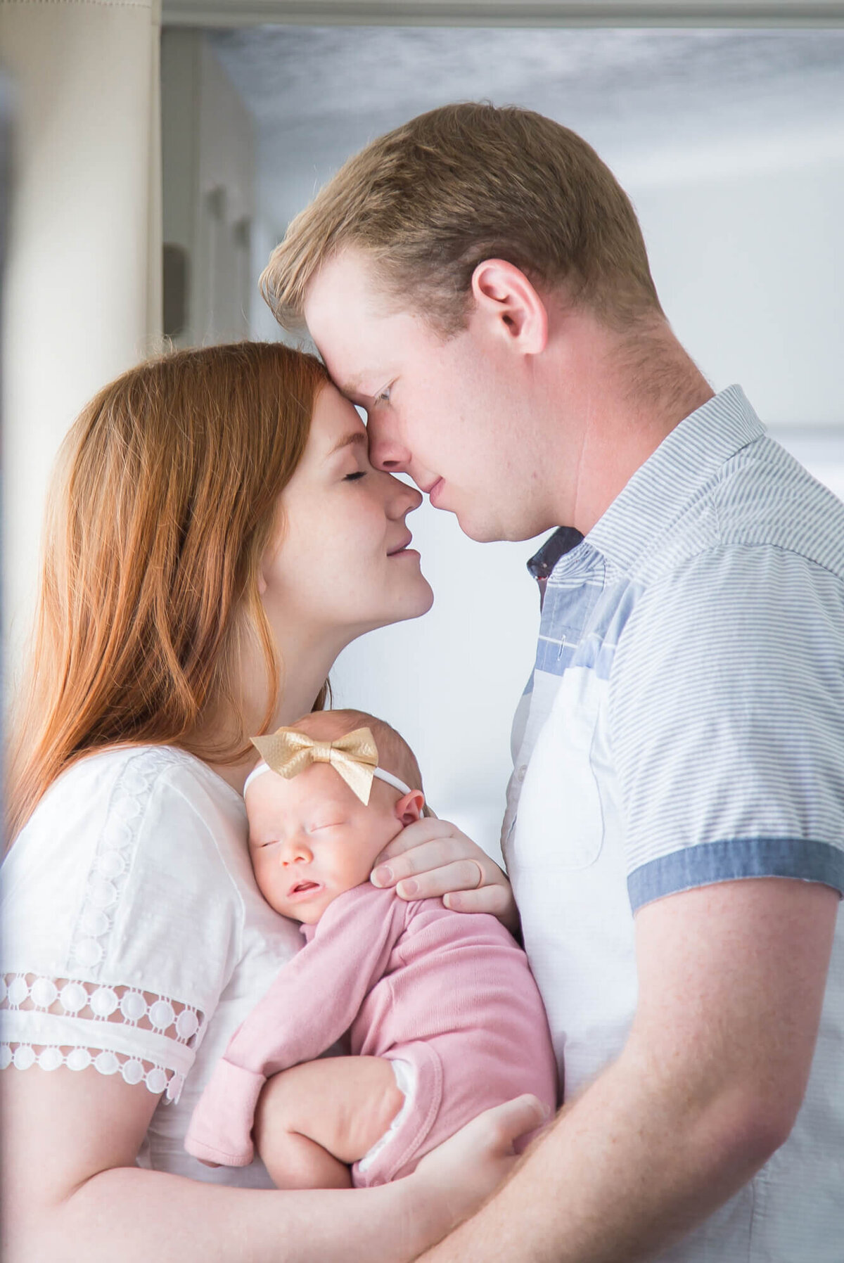 Couple with foreheads together holding  newborn baby girl