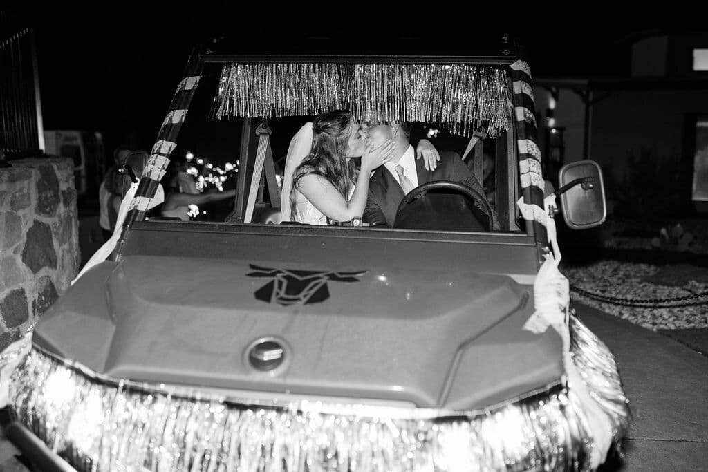 bride and groom kiss in car