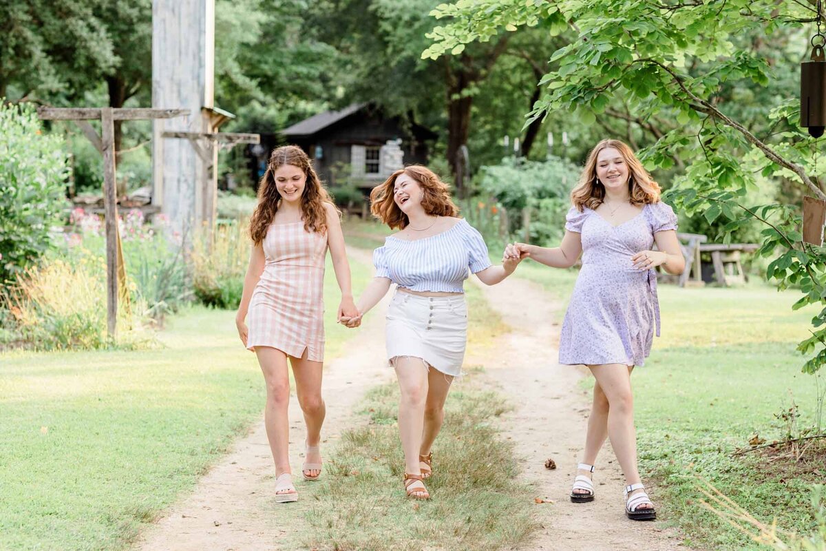 Three friends laughing and walking down a dirt path at Turnipseed Nursery in Fayetteville.