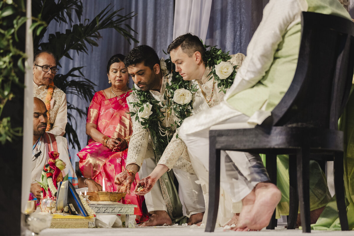 Two grooms placing an item into a bowl during a wedding ceremony 