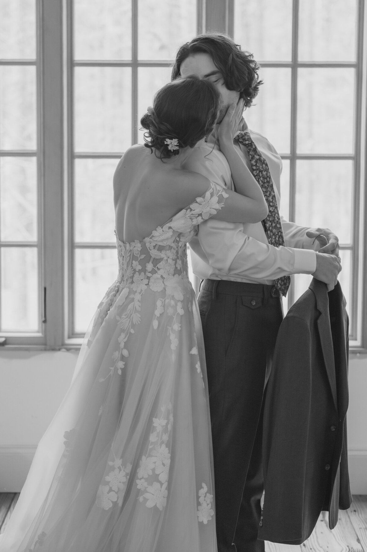 Newlyweds kiss on their wedding day in front of a window