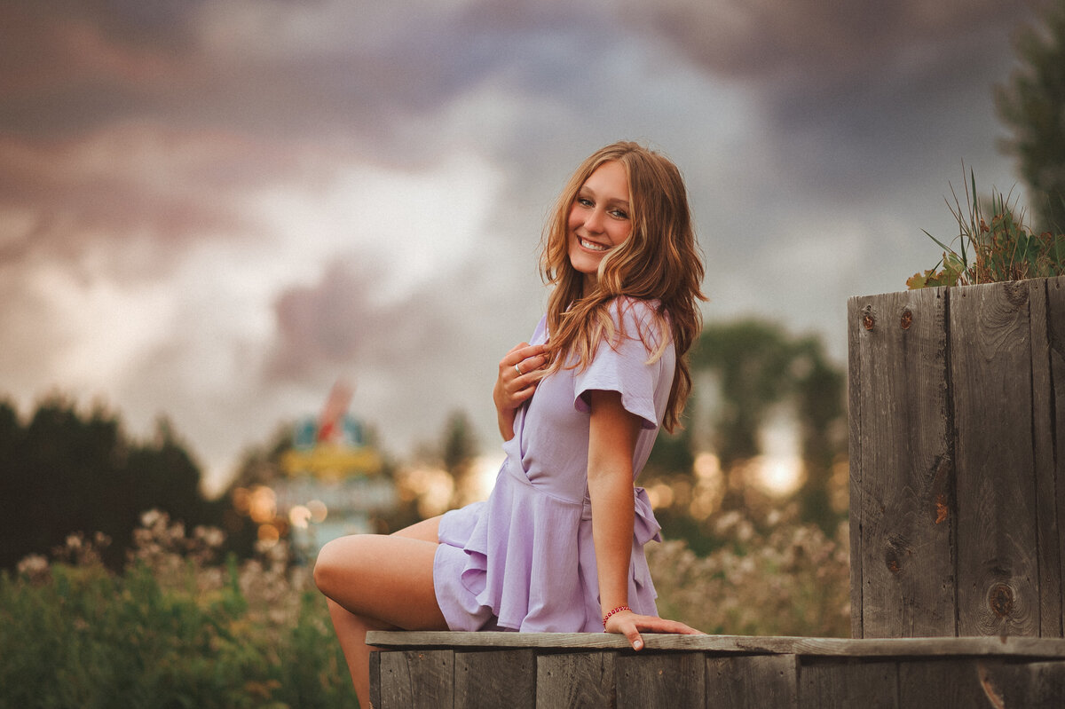 female high school senior sitting on the edge of a landing at Fraconia Sculpture garden at sunset