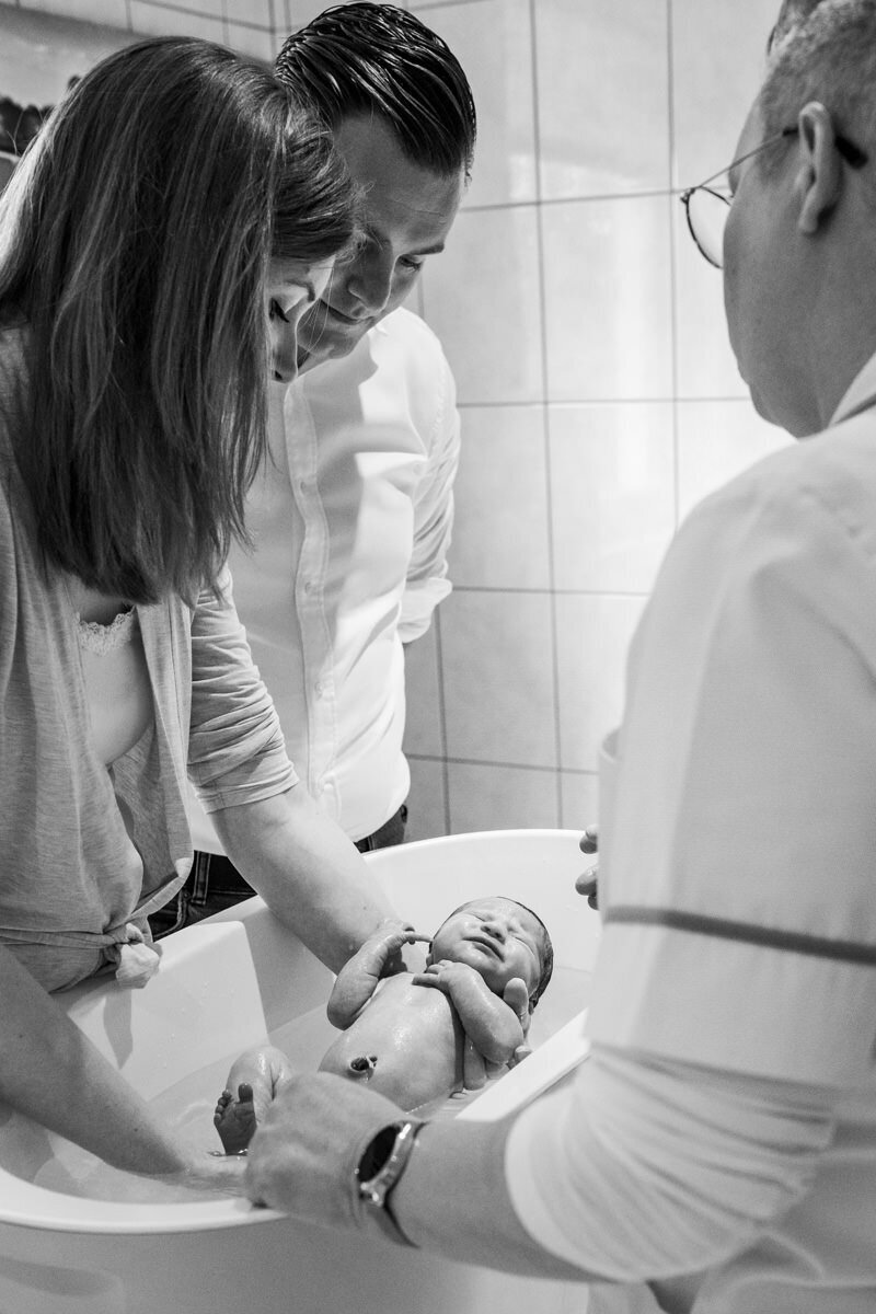 pasgeboren baby in badje doen