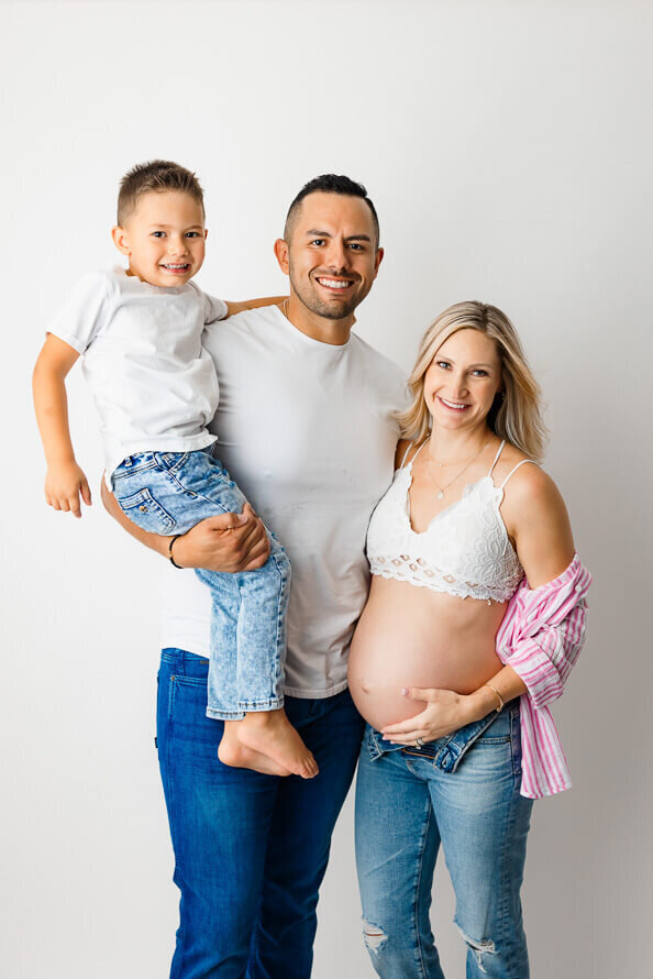 A family poses in a photography studio for their maternity photos.