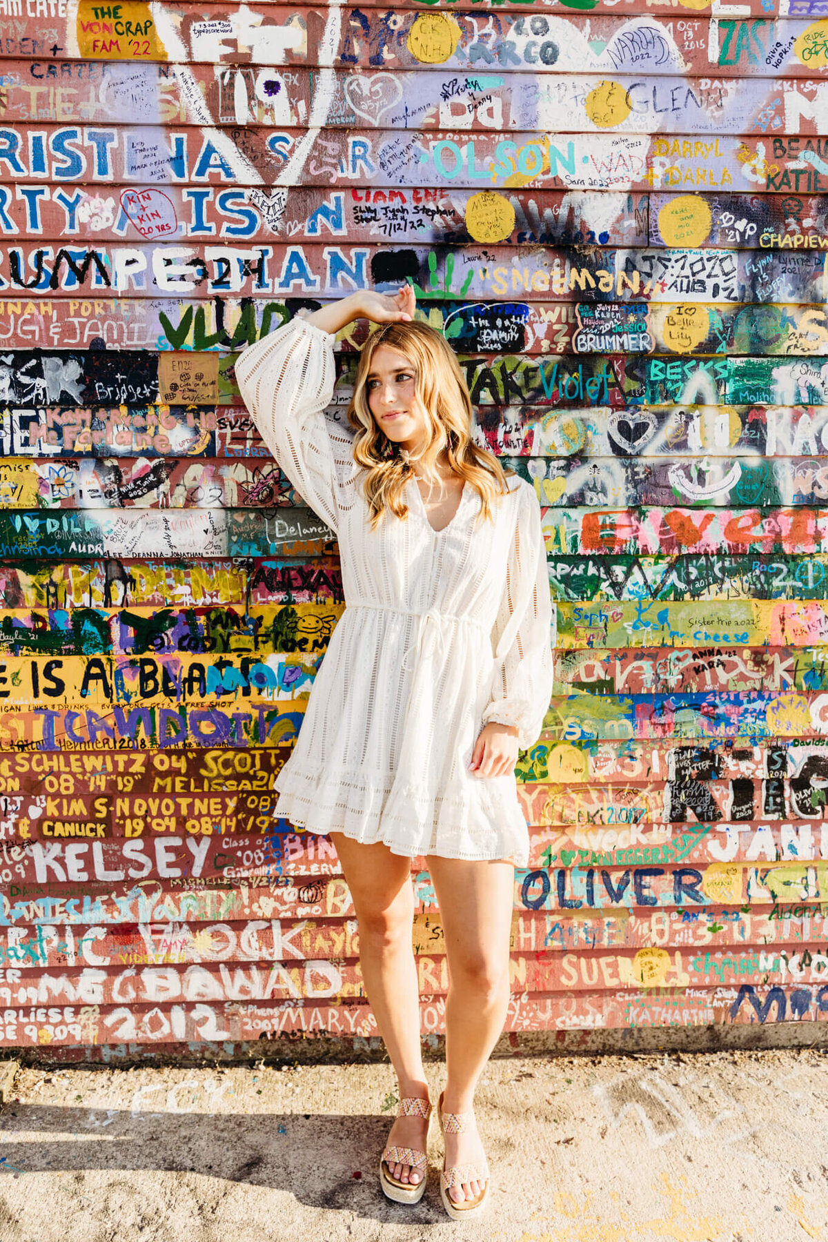 high school senior girl  leaning against a wall painted with names