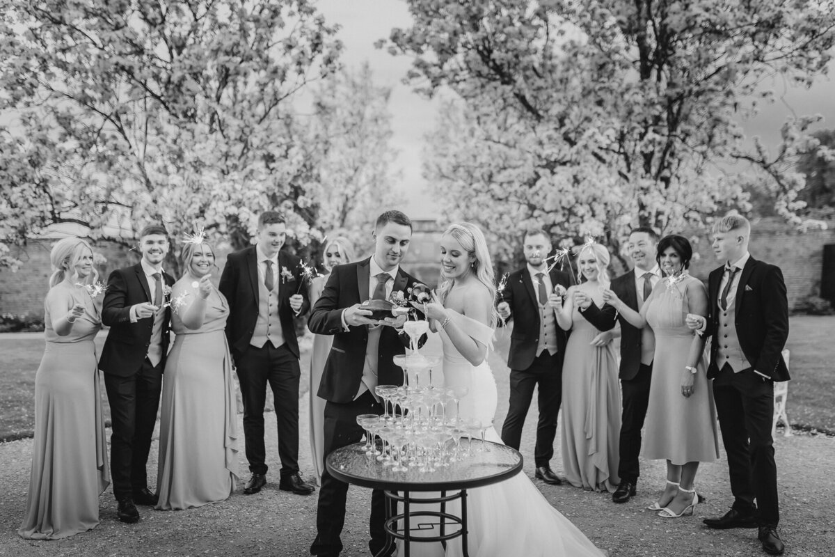 Bride and groom pouring champagne with family and friends holding sparklers