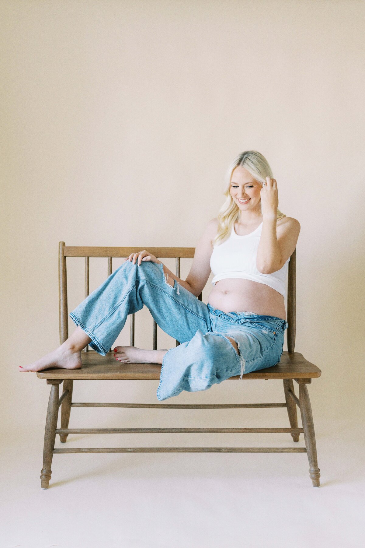 pregnant mom sitting on bench in casual clothes for maternity photo