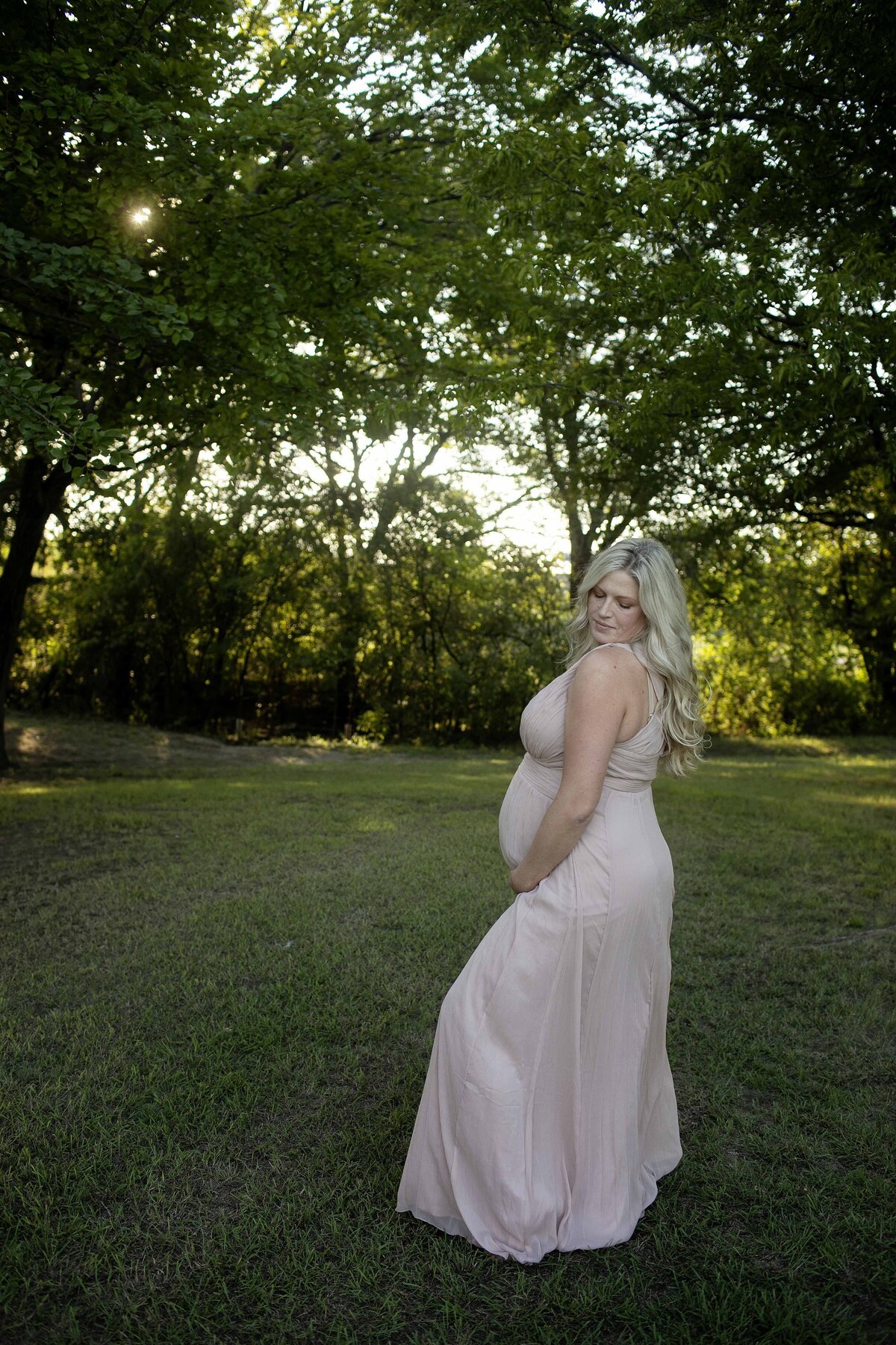 A serene maternity photo of the expectant mom standing with her hands lovingly wrapped around her belly, gazing down with a peaceful expression, captured by Chunky Monkey Photography.