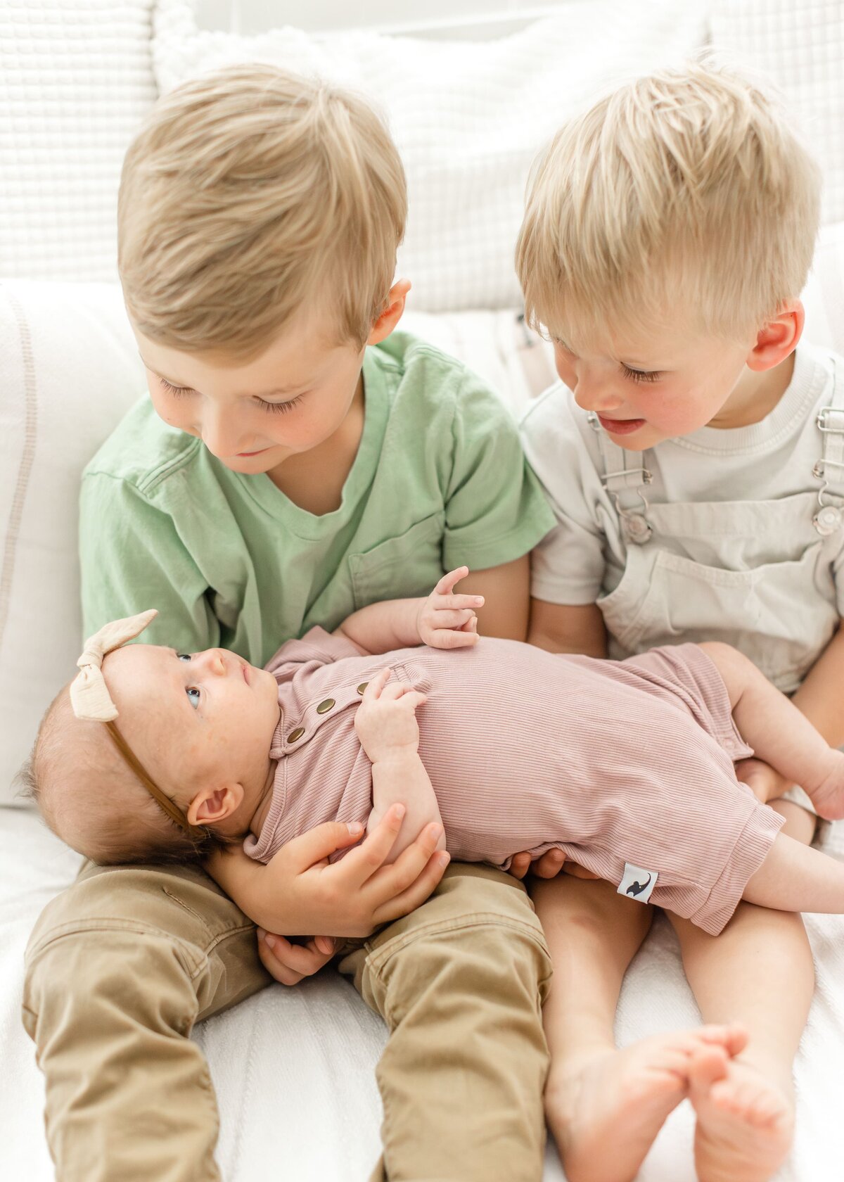 two boys holding their baby sister