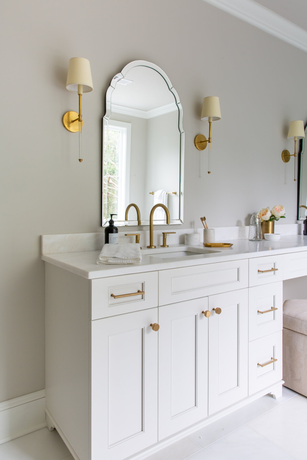 Bright bathroom in Kiawah Island, SC, featuring a white vanity, gold fixtures, and soft lighting.