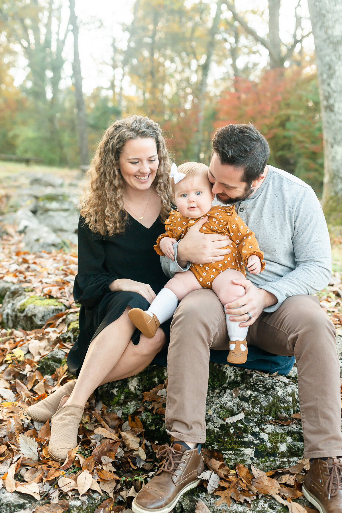 KY Photographer: Portrait of a mother and father holding their daughter and looking at her in fall.