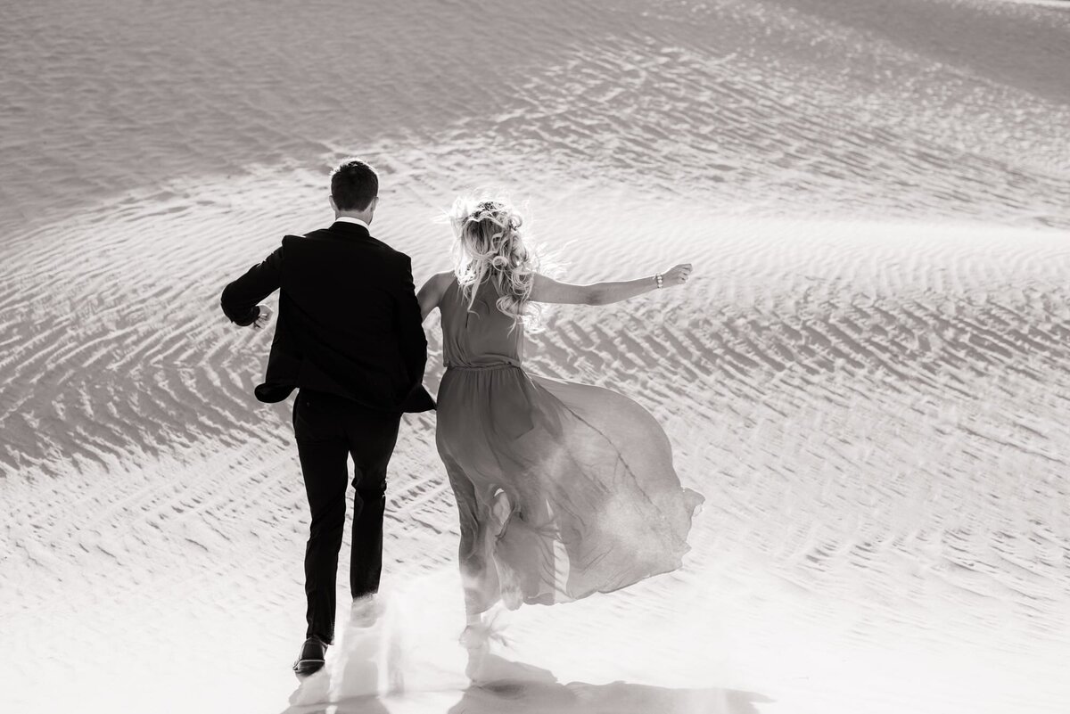 Couple running down a sand dune