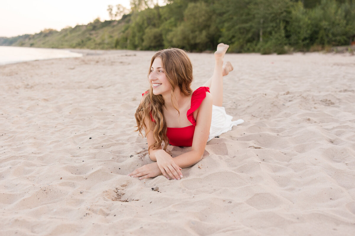 Senior girl laying on a beach and looking at Lake Michigan