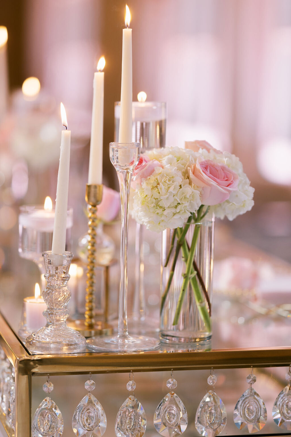 candles and roses sitting on a glass table with gold accents