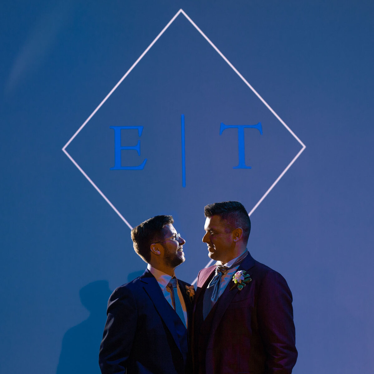 Two men in suits are standing next to each other in front of a blue background