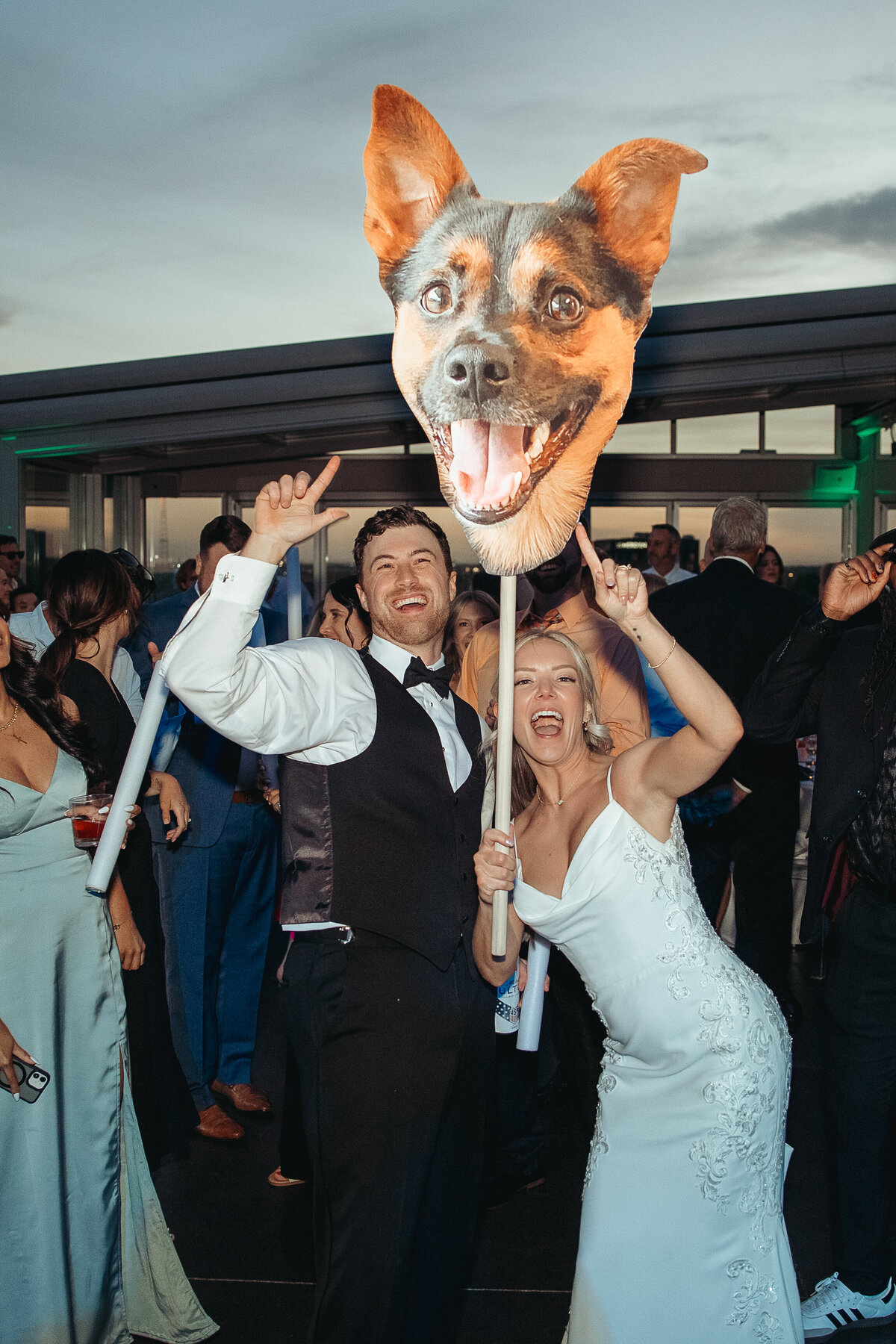 the bride and groom dancing wigth guests and holding a giant prop of a dog's head during their reception at Revery in Columbus, Ohio. 