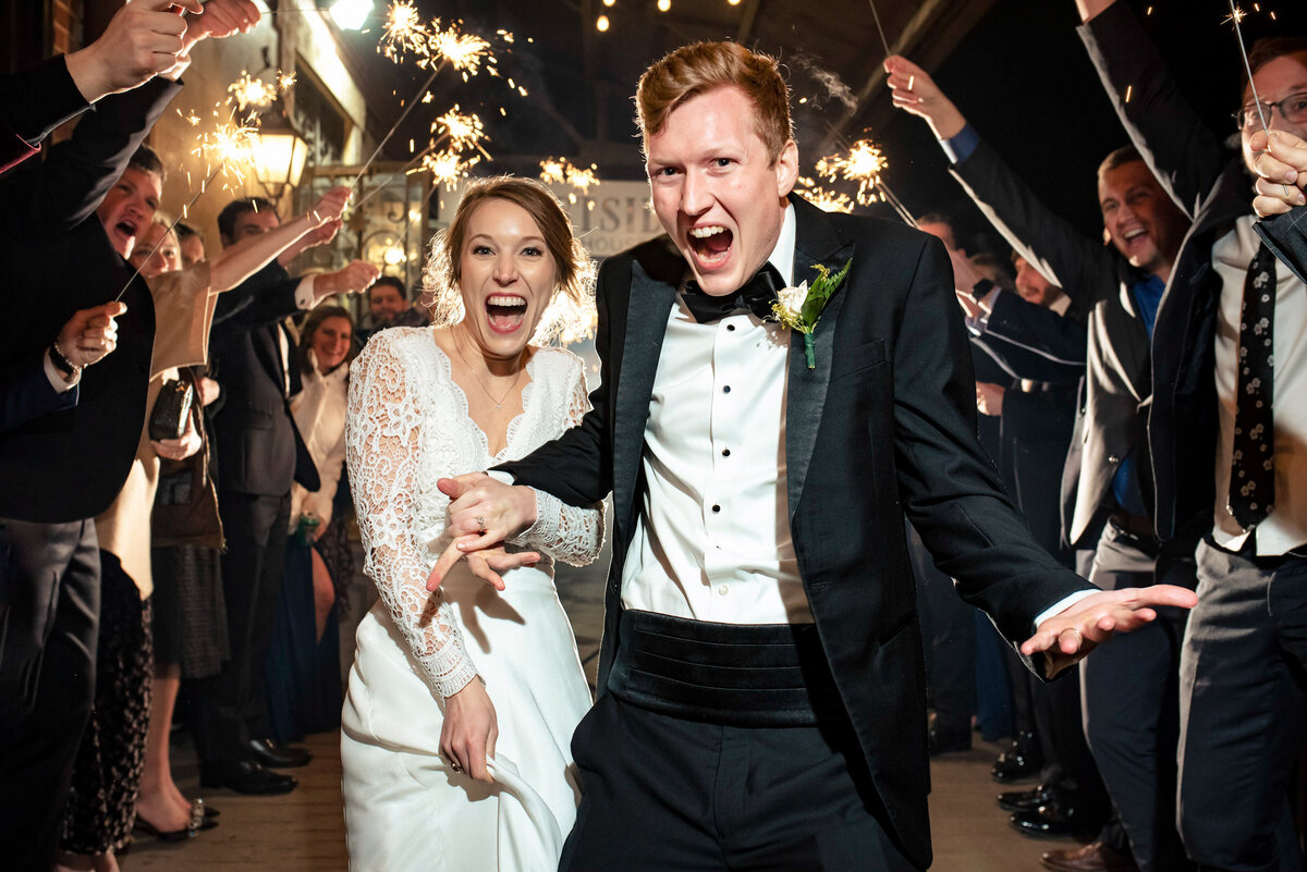 Candid-photograph-of-a-bride-and-groom-excitedly-running-down-the-sidewalk-outside-the-Westside-Warehouse-in-Atlanta-GA-during-their-sparkler-exit