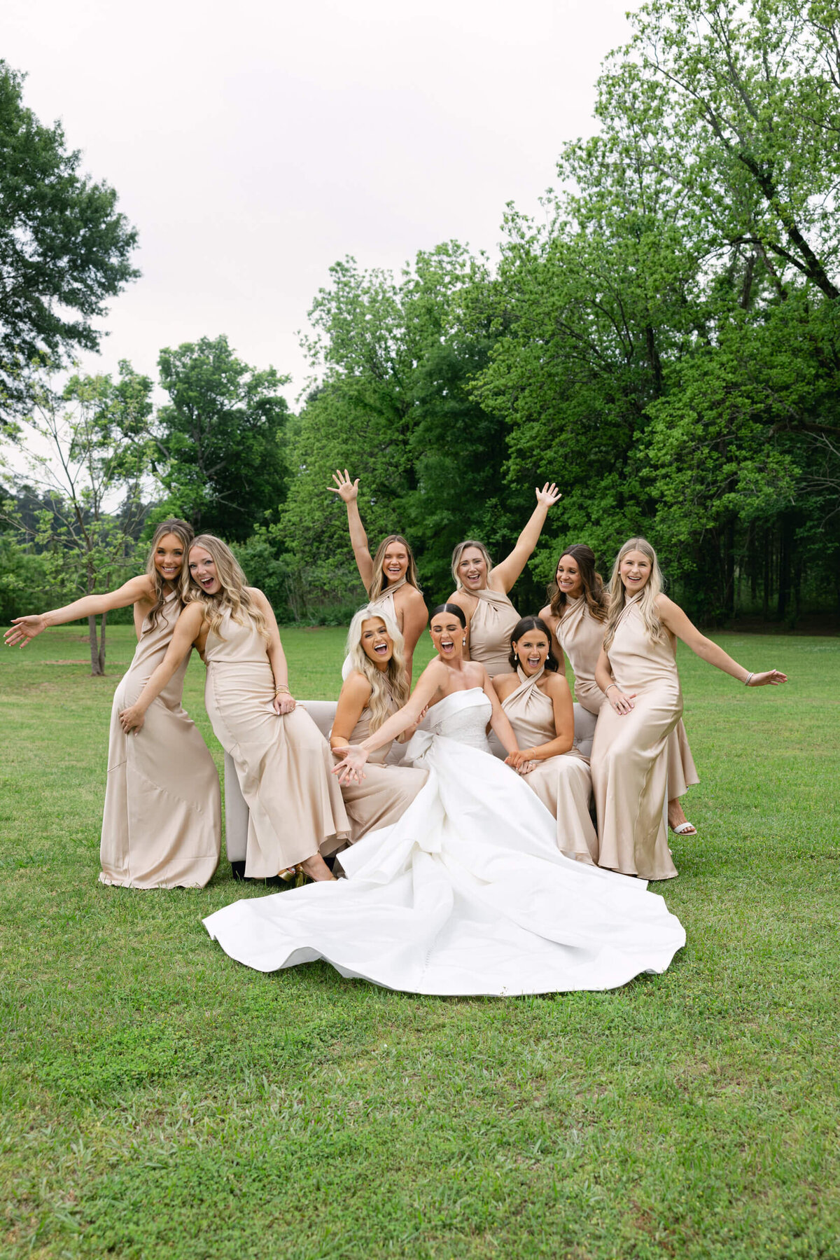 A wedding day portrait photo of the bride in her white wedding dress surrounded by her bridesmaids