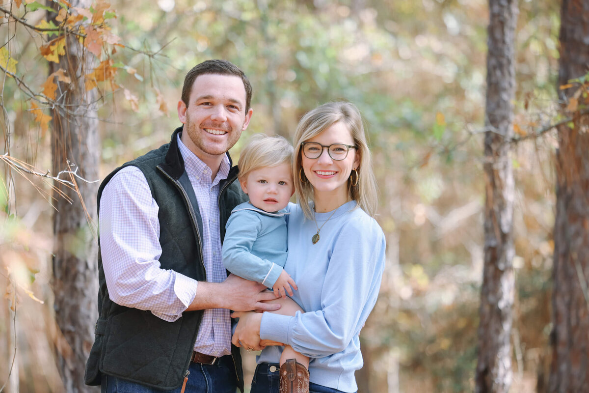 family-of-three-posing-in-woods