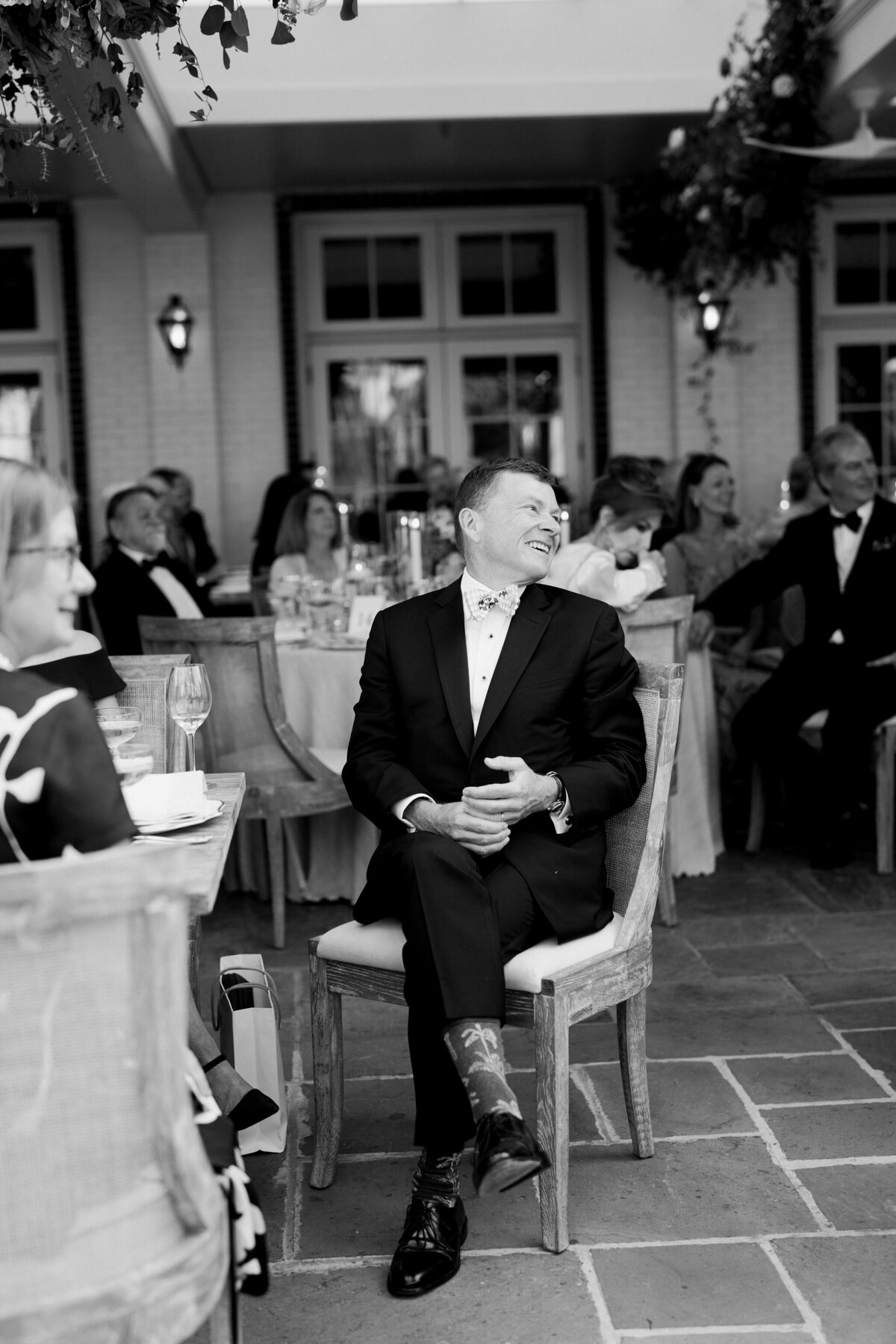 Black and white photo of the groom in a chair at the wedding. 