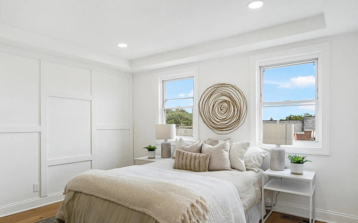 Bright and inviting bedroom remodel featuring custom wall paneling, natural light from dual windows, and a neutral color palette—designed for comfort and modern elegance.