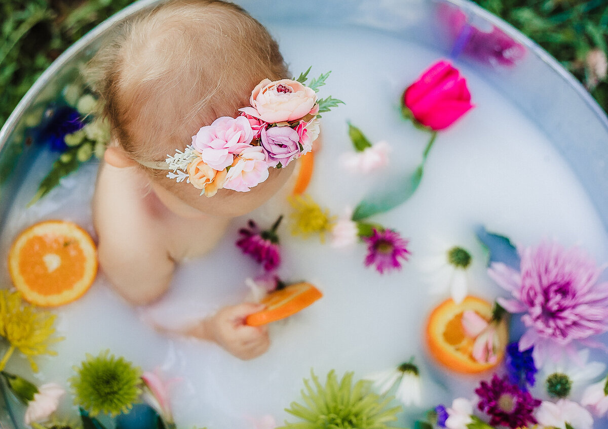 baby girl in metal tub milk bath with flowers
