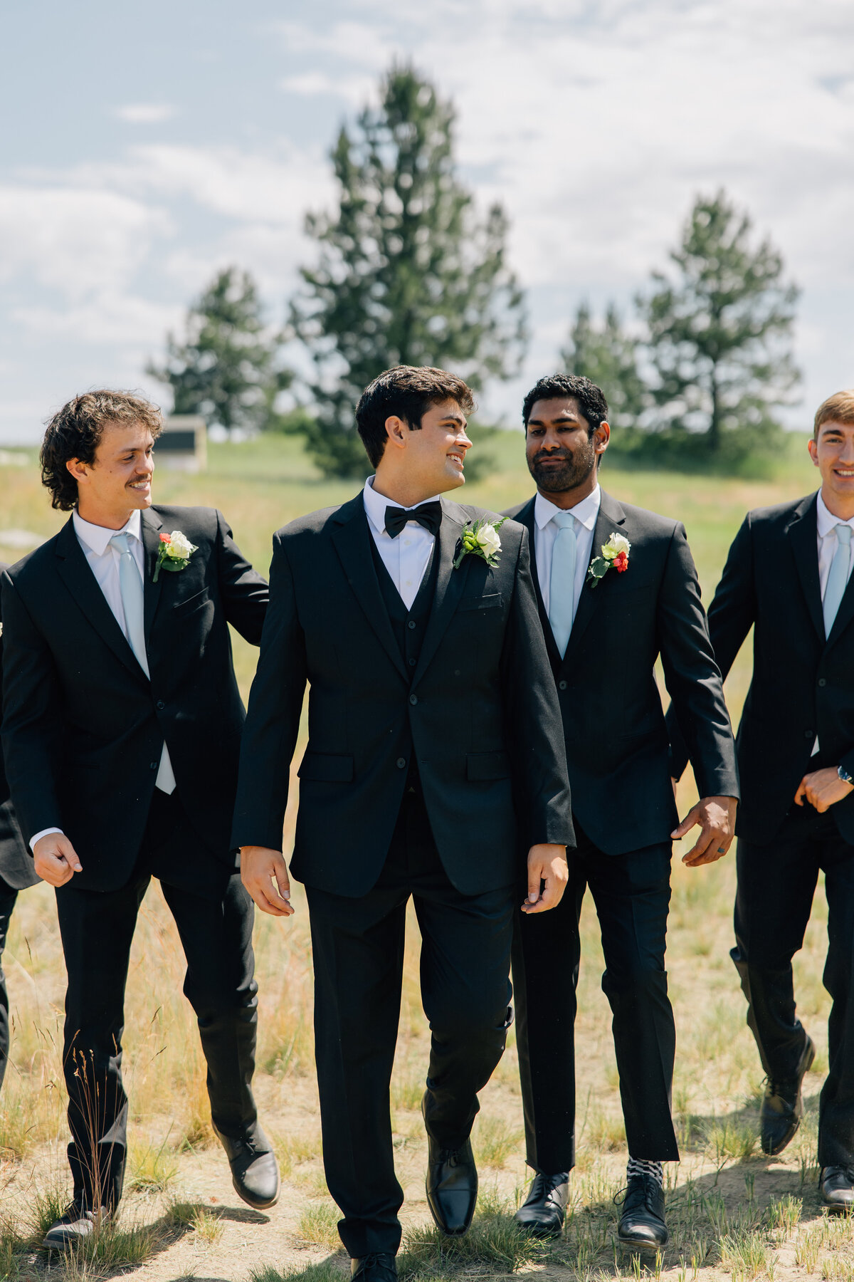 Groom & Groomsmen walking in a line with suits of black as they laugh together