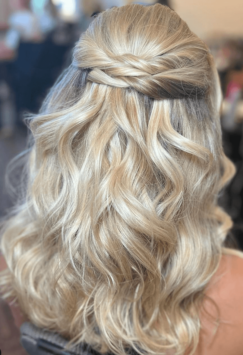 Elegant half-up hairstyle with twisted crown and soft curls, styled by bridal hairdresser in Austin for a formal wedding look