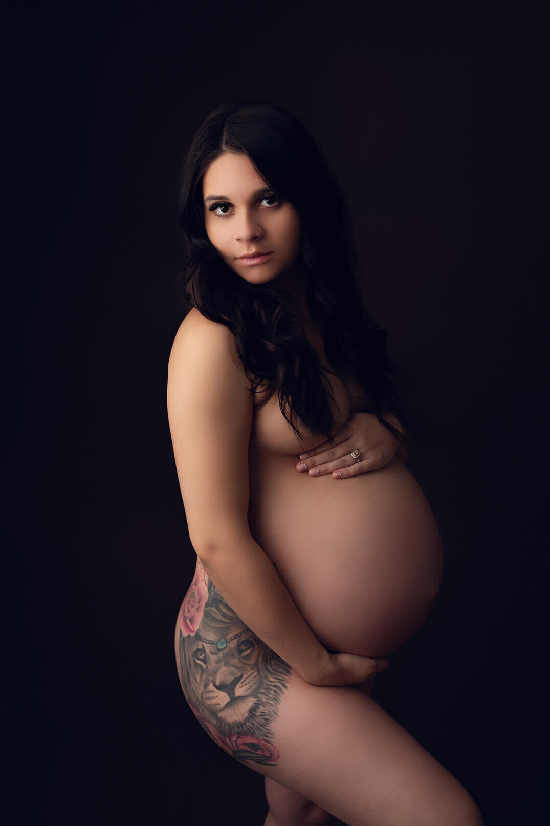 Completely nude pregnant woman holding bump