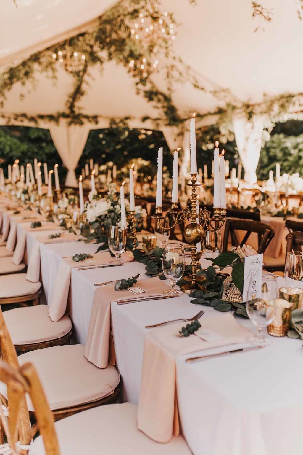 wedding reception with long tables, vineyard chairs, and greenery garlands with taper candles as centerpieces